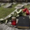 Czerwony znicz i kwiaty na płycie nagrobka